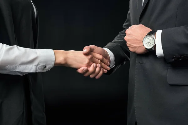 Cropped view of businesspeople shaking hands, isolated on black — Stock Photo