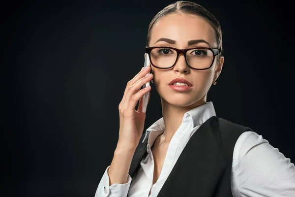 Joven empresaria confiada hablando en el teléfono inteligente, aislado en negro - foto de stock