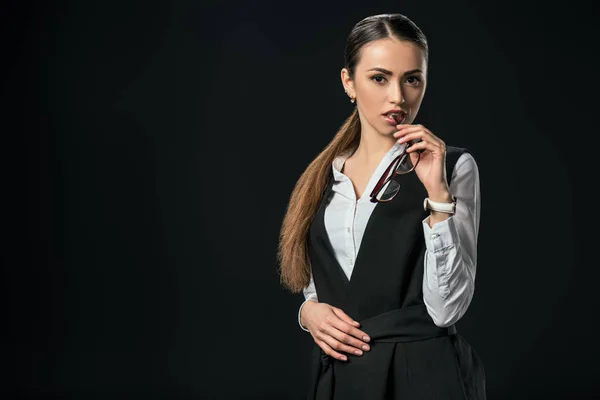 Young beautiful businesswoman holding eyeglasses, isolated on black — Stock Photo