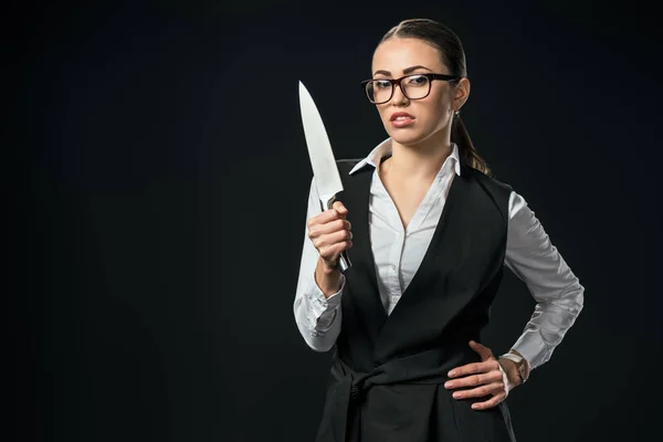 Молода впевнена бізнес-леді тримає ніж, ізольована на чорному — стокове фото