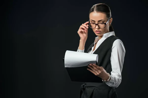 Donna d'affari fiduciosa in possesso di documenti negli appunti, isolato su nero — Foto stock