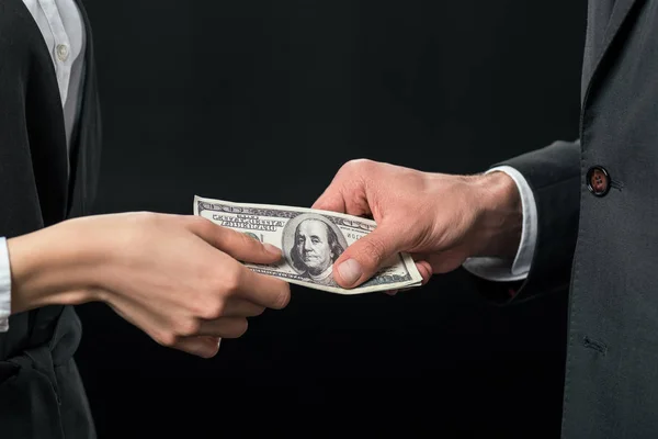Cropped view of businesspeople holding bribe, corruption concept, isolated on black — Stock Photo