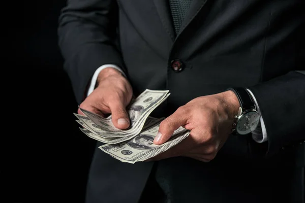 Cropped view of businessman holding dollar banknotes, isolated on black — Stock Photo