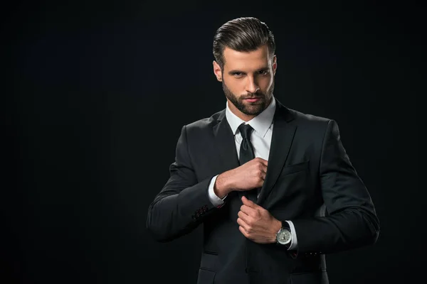 Handsome businessman taking something from pocket of jacket, isolated on black — Stock Photo