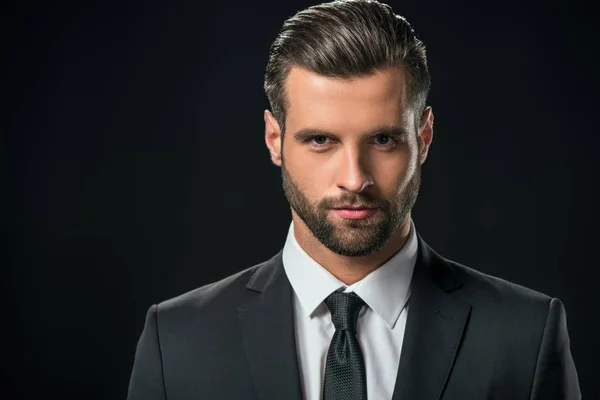 Handsome businessman in jacket looking at camera, isolated on black — Stock Photo