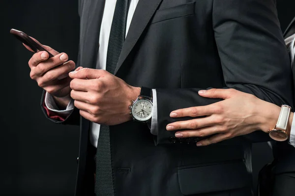 Vista recortada de hombre de negocios usando teléfono inteligente, aislado en negro - foto de stock