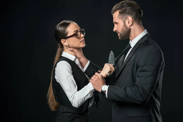 Socios comerciales que sostienen cuchillo y peleas aislados en negro - foto de stock