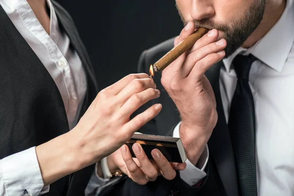 Cropped view of female secretary lightning cigar for boss, isolated on black — Stock Photo