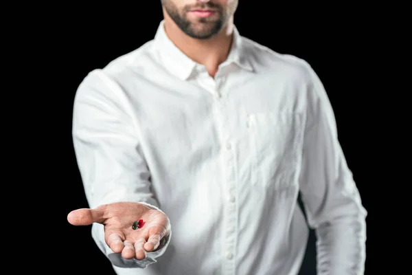 Abgeschnittene Ansicht eines Geschäftsmannes mit blauen und roten Pillen, isoliert auf schwarz — Stockfoto