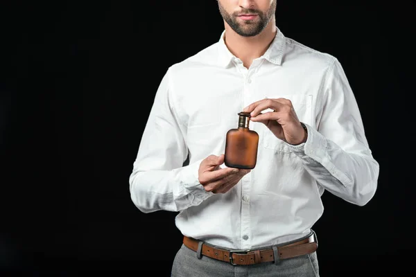 Обрізаний вид бізнесмена в білій сорочці, що тримає парфуми, ізольовані на чорному — стокове фото