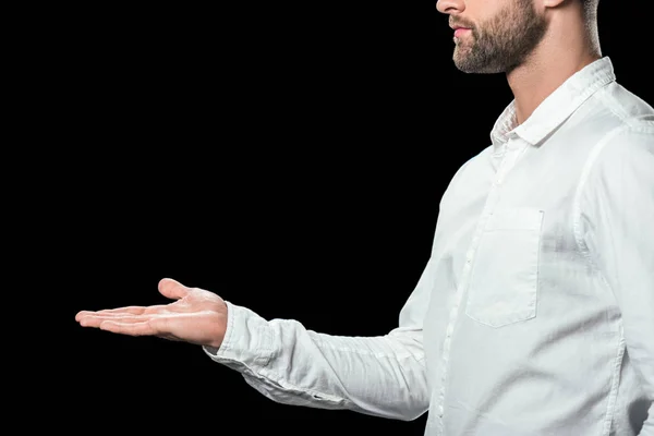 Recortado vista de hombre de negocios en camisa blanca presentando algo, aislado en negro - foto de stock