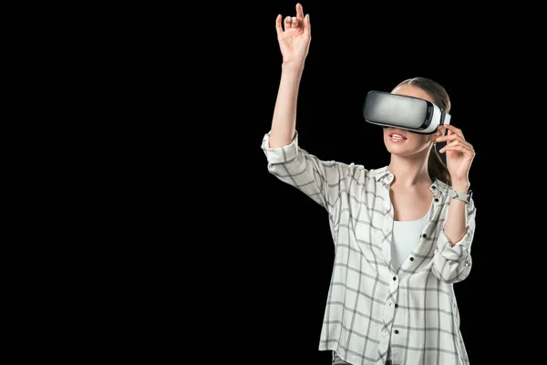 Fille gestuelle et en utilisant la réalité virtuelle casque, isolé sur noir — Photo de stock