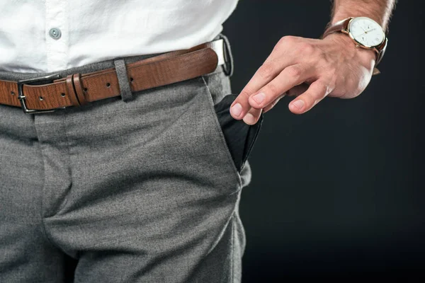 Vista recortada de hombre de negocios pobre con bolsillo vacío, aislado en negro - foto de stock