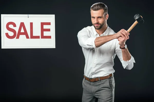 Hombre de negocios guapo con el cartel del martillo y de la venta, aislado en negro - foto de stock