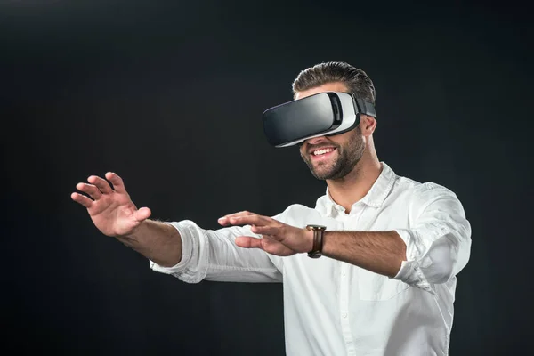 Hombre sonriente con auriculares de realidad virtual, aislado en negro - foto de stock