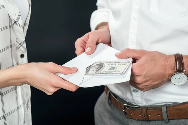 Обрезанный вид бизнесменов, держащих конверт с деньгами, изолированных на черном — стоковое фото
