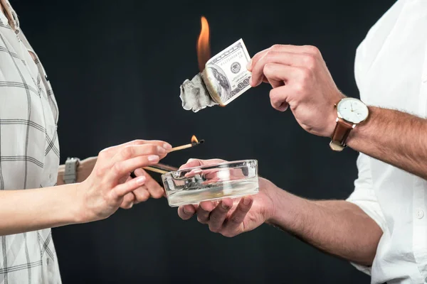 Cropped view of businesspeople burning dollar banknotes, isolated on black — Stock Photo