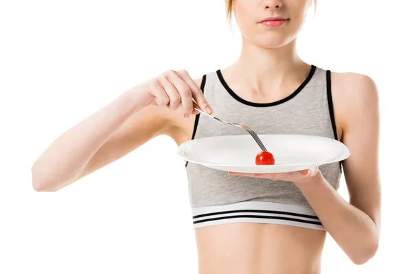 Young slim woman eating tiny cherry tomato from plate isolated on white — Stock Photo