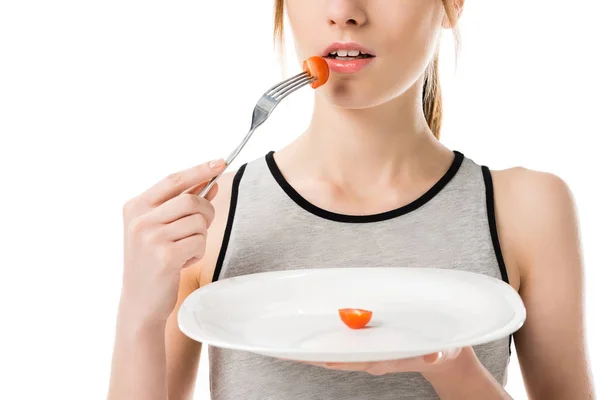 Tiro recortado de mujer delgada comiendo tomate cereza diminuta aislado en blanco - foto de stock
