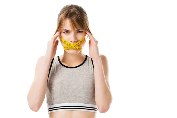 Young woman with measuring tape tied around her mouth having headache isolated on white — Stock Photo