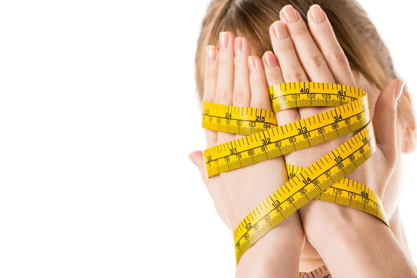 Close-up shot of woman covering face with hands tied in measuring tape isolated on white — Stock Photo