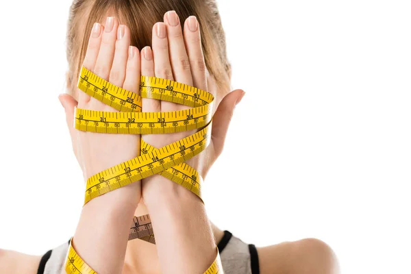 Woman covering face with hands tied in measuring tape isolated on white — Stock Photo