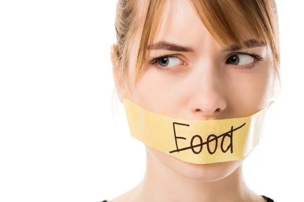 Mujer joven con cinta adhesiva con tachado a través de la palabra comida que cubre la boca aislada en blanco - foto de stock