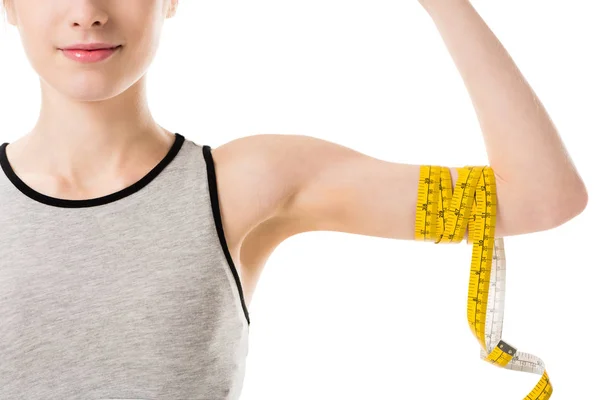 Foto recortada de una joven mostrando sus bíceps atados con cinta métrica aislada en blanco - foto de stock