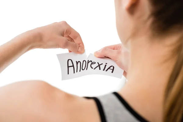 Обрезанный снимок женщины, рвущей бумагу с надписью анорексии, изолированной на белом — стоковое фото