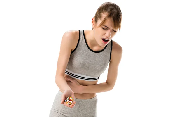 Mujer joven con dolor de estómago sosteniendo pastillas aisladas en blanco - foto de stock