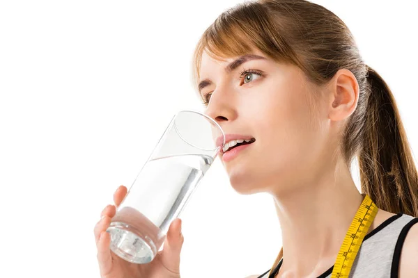 Young woman with measuring tape on neck drinking water isolated on white — Stock Photo