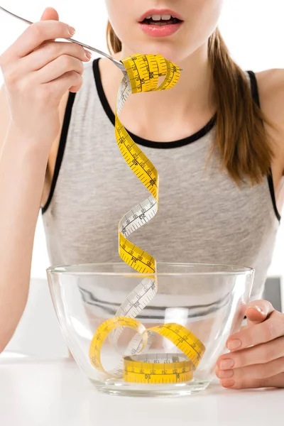 Abgeschnittene Aufnahme einer Frau beim Essen von Maßband isoliert auf weißem, Anorexie-Konzept — Stockfoto