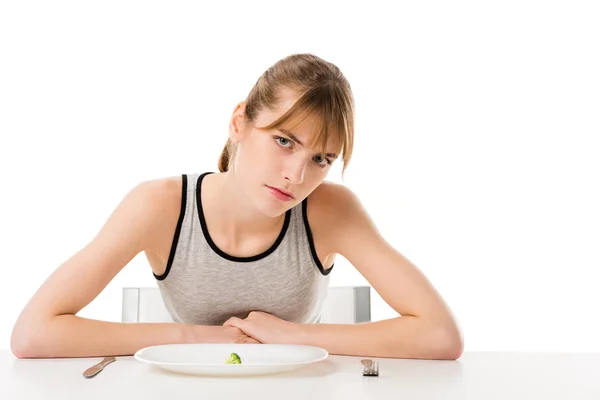 Depressed slim woman with piece of broccoli on plate isolated on white — Stock Photo