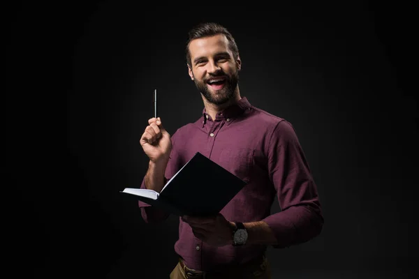 Portrait of excited businessman with notebook isolated on black — Stock Photo