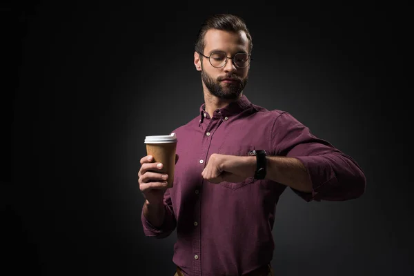 Porträt eines Geschäftsmannes mit Coffee to go und Zeitkontrolle isoliert auf schwarz — Stockfoto