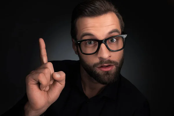 Portrait of man in eyeglasses pointing up isolated on black — Stock Photo