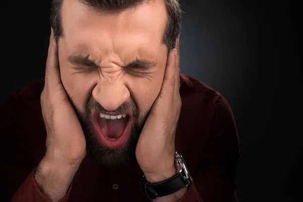 Портрет кричущого чоловіка, що закриває вуха, ізольовані на чорному — стокове фото