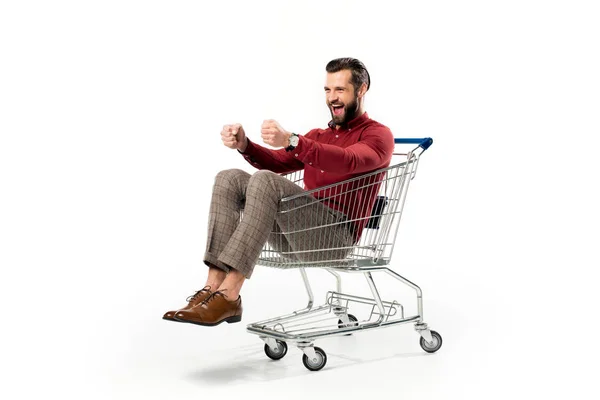 Homem alegre sentado no carrinho de compras isolado no branco — Fotografia de Stock