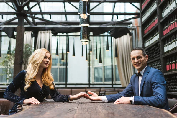 Side view of happy adult couple holding hands at restaurant — Stock Photo