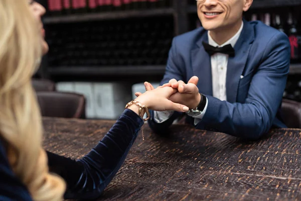 Recortado disparo de pareja teniendo fecha en restaurante y cogido de la mano - foto de stock