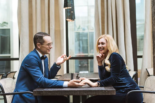 Seitenansicht eines glücklichen erwachsenen Paares beim Date im Restaurant und Händchenhalten — Stockfoto