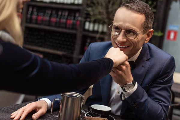 Hombre adulto feliz besando la mano de la novia en el restaurante - foto de stock