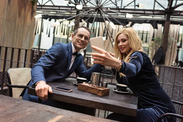 Hermosa pareja adulta tomando selfie en restaurante - foto de stock