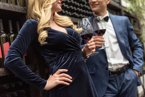 Plan recadré de beau couple adulte buvant du vin devant les étagères de stockage de vin — Photo de stock