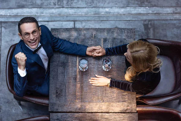 Top view of beautiful adult couple holding hands at restaurant while drinking wine — Stock Photo