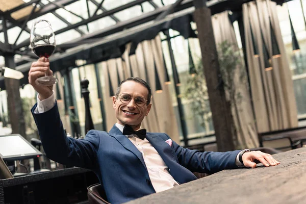 Hombre adulto feliz en traje elegante con copa de vino tinto en el restaurante - foto de stock