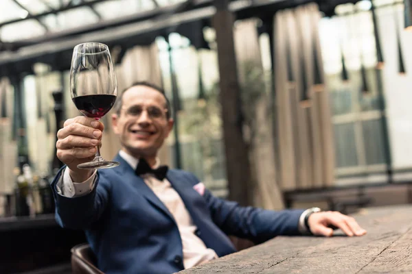 Bell'uomo in abito elegante con bicchiere di vino rosso al ristorante — Foto stock