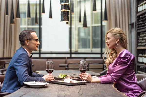 Seitenansicht eines schönen erwachsenen Paares bei einem Date im Luxusrestaurant — Stockfoto