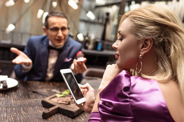 Homem propondo sua namorada enquanto ela usando smartphone no restaurante — Fotografia de Stock