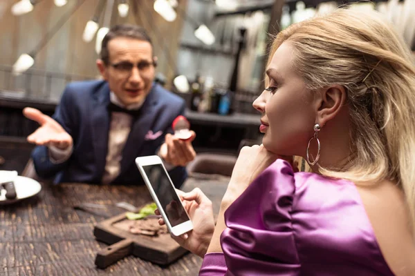 Man proposing his girlfriend while she using smartphone at restaurant — Stock Photo